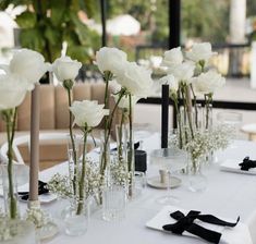 there are many white flowers in vases on the table