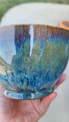 a person holding a blue and green bowl in their hand