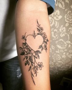 a woman with a tattoo on her arm holding a flower and heart shaped frame in the center