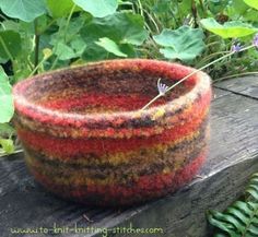 a bowl sitting on top of a wooden table next to green plants and flowers in the background