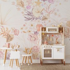 a toy kitchen with floral wallpaper in the background