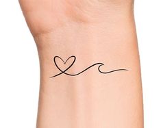 a woman's wrist with a small heart tattoo on the left side of her arm