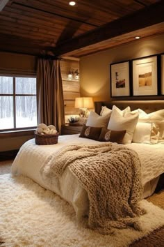 a large bed sitting in a bedroom next to a window covered in blankets and pillows