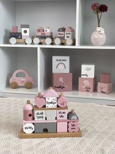 pink and white wooden toys are on display in a room with shelving, bookshelves and flowers