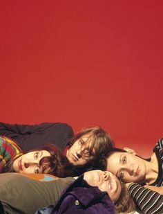 four people are laying on the floor in front of a red wall