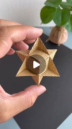 a person is holding an origami star in their left hand and the other hand is pointing at it