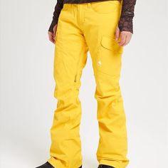 a man wearing yellow snow pants and black shoes standing in front of a white background