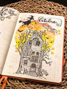 an open notebook on top of a wicker basket filled with halloween decorations and writing