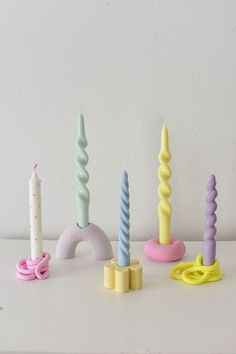 there are many candles that are on the table and one is pink, blue, green, yellow