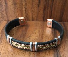 a black leather bracelet with two metal clasps on a wooden surface and wood background