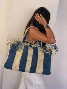 a woman carrying a large blue and white striped tote bag with straw on it