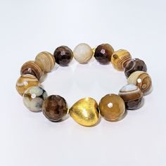 This Ro & Gieo bracelet features stunning banded agate beads paired with a chunky 24 karat gold-plated brass heart. The unique combination of materials offers a luxurious and trendy look, making it the perfect accessory for any occasion. The banded agate beads provide a natural and earthy touch, while the gold-plated heart adds a touch of elegance. Elevate your style with this exquisite bracelet. Ro & Gieo Banded Agate Bead and 24 karat gold-plated 100% brass heart chunky bracelet Beads - 16 mm Gold Agate Beaded Bracelets With Gemstones, Gold Agate Gemstone Beaded Bracelets, Gold Agate Gemstone Beaded Bracelet, Gold Agate Gemstone Bracelets, Luxury Adjustable Heart-shaped Bracelet, Gold Agate Bracelet With Gemstone Beads, Gold Heart-shaped Gemstone Bracelets, Gold Bracelets With Agate And Natural Stones, Gold Heart-shaped Jewelry With Faceted Beads