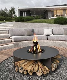 a fire pit sitting on top of a wooden floor next to a pile of logs