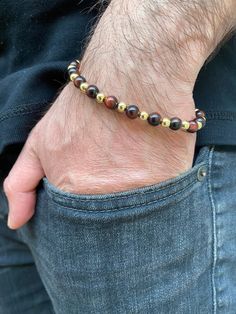 Red Tiger Eye Stone with Gold Ball Bead Bracelet, Men's Gold Accessory, 18K Gold Men's Jewelry. Your favorite daily stackable! Ladies lets not forget the men in our lives, surprise your dad, brother, husband, boyfriend, or your best friend with this elegant stretch style ball bead bracelet. Beautiful rich red tiger's eye bead bracelet, Tigereye is said to combine earth energy with light or sun energy, creating an intense stone that's also well-grounded. Tigereye is said to enhance psychic and em Elegant Hand-strung Bracelets, Gold Bracelets With Gemstone Beads For Formal Occasions, Gold Wristband With 8mm Beads, Formal Gold Bracelets With Gemstone Beads, Eye Bead Bracelet, Sun Energy, Earth Energy, Red Tiger, Red Tigers Eye