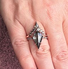 a woman's hand with a ring on top of it and an arrow shaped diamond in the middle