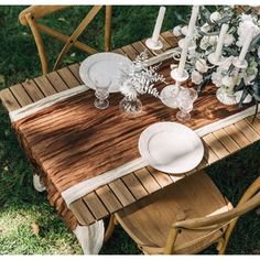 a wooden table topped with white plates and flowers