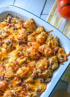 a casserole dish with cheese and tomatoes on the side, ready to be eaten