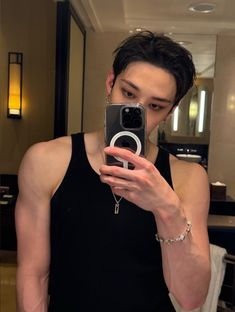 a man taking a selfie with his cell phone in front of him and wearing a black tank top