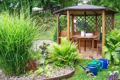 a small wooden gazebo surrounded by lush green plants