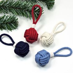 three different colored ropes tied to each other on a white surface with pine branches in the background