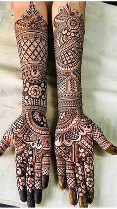 two hands with henna tattoos on them, one is showing the intricate pattern and the other has an ornate design