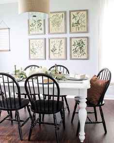 a white table with black chairs and pictures on the wall