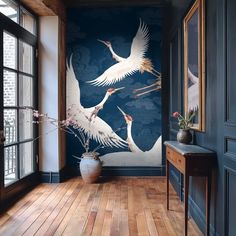 two white birds flying over a wooden floor in front of a blue wallpapered room