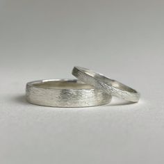 two silver wedding rings sitting on top of each other