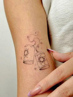 a woman's arm with a tattoo on it that has two cups and stars in them