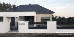 a white house with a black roof and fence