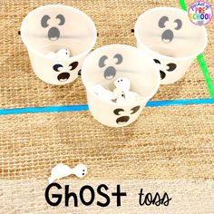 three cups with ghost faces in them on a burlocked tablecloth background