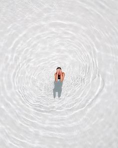 a man floating in the middle of a body of water with his back turned to the camera