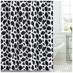 a shower curtain with black and white animal print on the outside, in front of a window