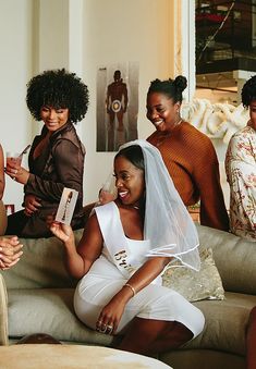 a group of women sitting on top of a couch next to each other holding boxes