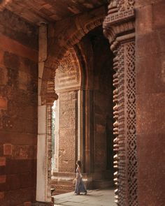 a woman is standing in an archway between two stone buildings with carvings on the walls