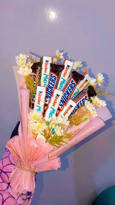 a bouquet of flowers and chocolate bars in a pink wrapper on top of a table