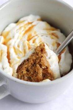 a cup filled with ice cream and caramel sauce on top of a white table