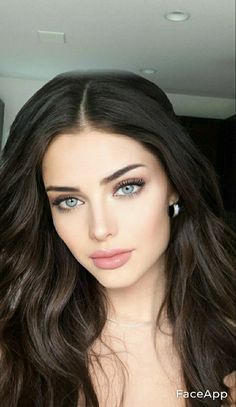 a woman with long dark hair and blue eyes is posing for a photo in the mirror