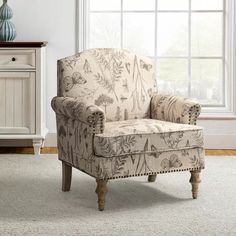 a chair sitting on top of a white rug in front of a window next to a dresser