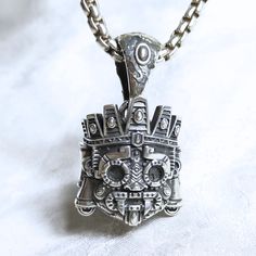 .925 Sterling Silver. Height is 30mm (1.181"), Width is 25mm (0.98"). Bail fits 8.9mm chain. Aztec deity Tlaloc is that he was associated with both life-giving and destructive aspects of water. Tlaloc was the god of rain, fertility, and water, and he played a crucial role in Aztec mythology and religious practices. Tlaloc was often depicted with goggle-like eyes and fangs, and he was sometimes shown with a headdress resembling a mountain or a stepped pyramid. His dual nature is reflected in the Sterling Silver Box Chain Necklace In Spiritual Style, Silver Amulet Necklace With Chain, Spiritual Sterling Silver Box Chain Jewelry, Aztec Pendant, Sterling Silver Box Chain Spiritual Necklace, Nickel-free Stainless Steel Skull Necklace, Great Conversation Starters, Headdress, Precious Metals