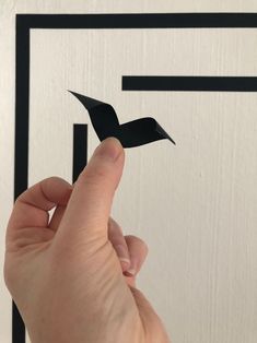 a hand is holding a piece of paper that looks like an origami bird