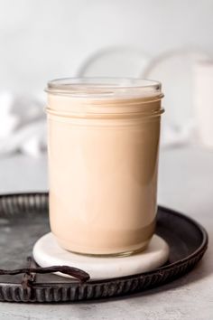 a glass jar sitting on top of a black plate next to a spoon and fork