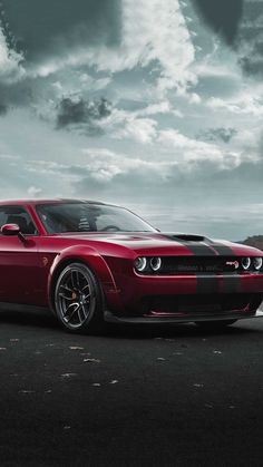 a red sports car parked in front of a cloudy sky