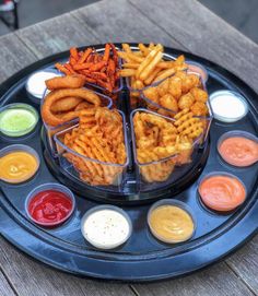 a platter filled with different types of food on top of a wooden table next to dipping sauces and ketchup