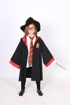 a young child dressed in harry potter costume and holding a wand with both hands, standing on a white background