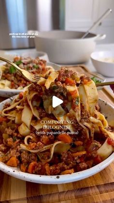 a bowl filled with pasta and meat on top of a wooden table