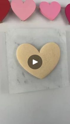 a heart shaped cookie sitting on top of a piece of paper next to other hearts