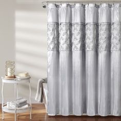 a white shower curtain in a bathroom with wood flooring and wooden table next to it