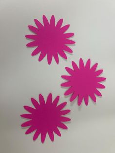 three pink paper flowers on a white surface