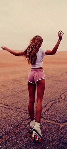 a woman is skateboarding in the middle of an empty parking lot with her arms outstretched